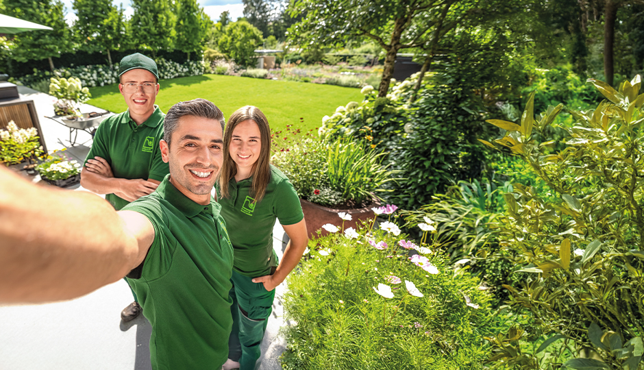 Landschaftsgärtner machen Selfie vor einem Garten und zeigen Stolz ihre Arbeit