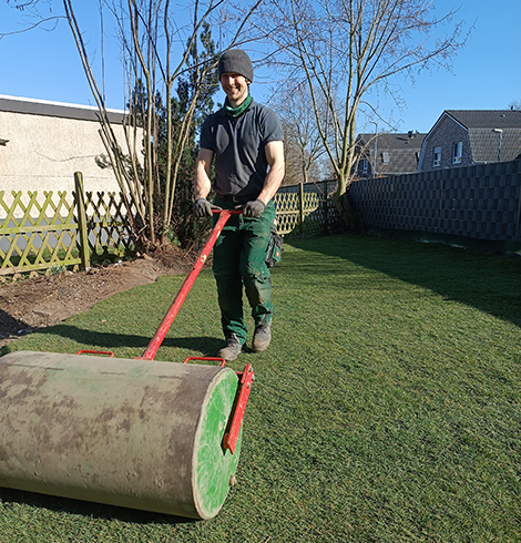 Simon arbeitet in einem Garten mit einem Gartengerät für die Wiese