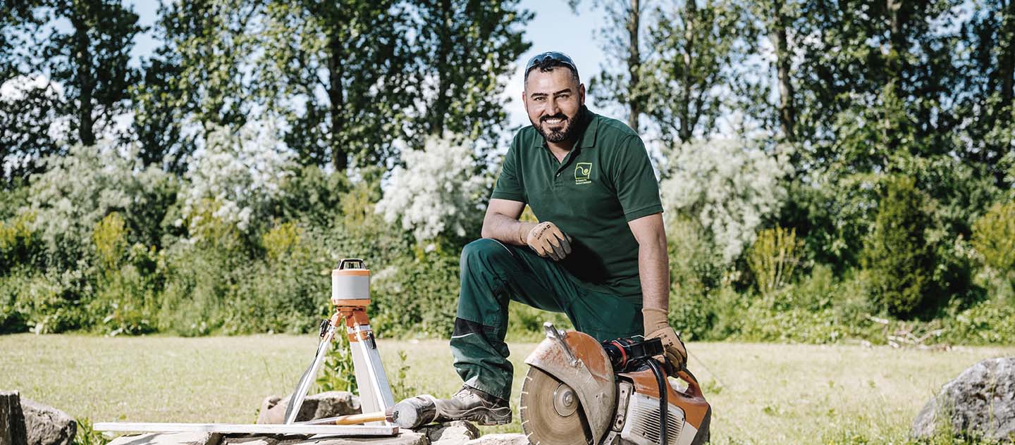 Landschaftsgärtner präsentiert sich hinter seiner Arbeit am Naturstein