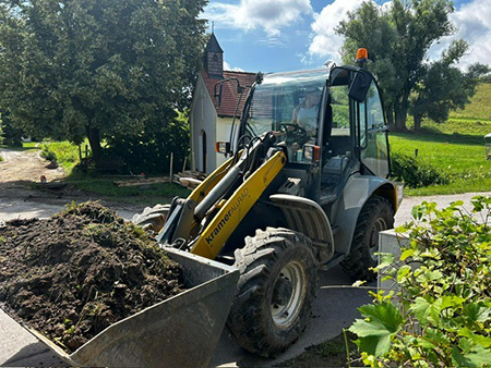 Radlader fährt über eine Strasse in Bayern und bewegt Erde